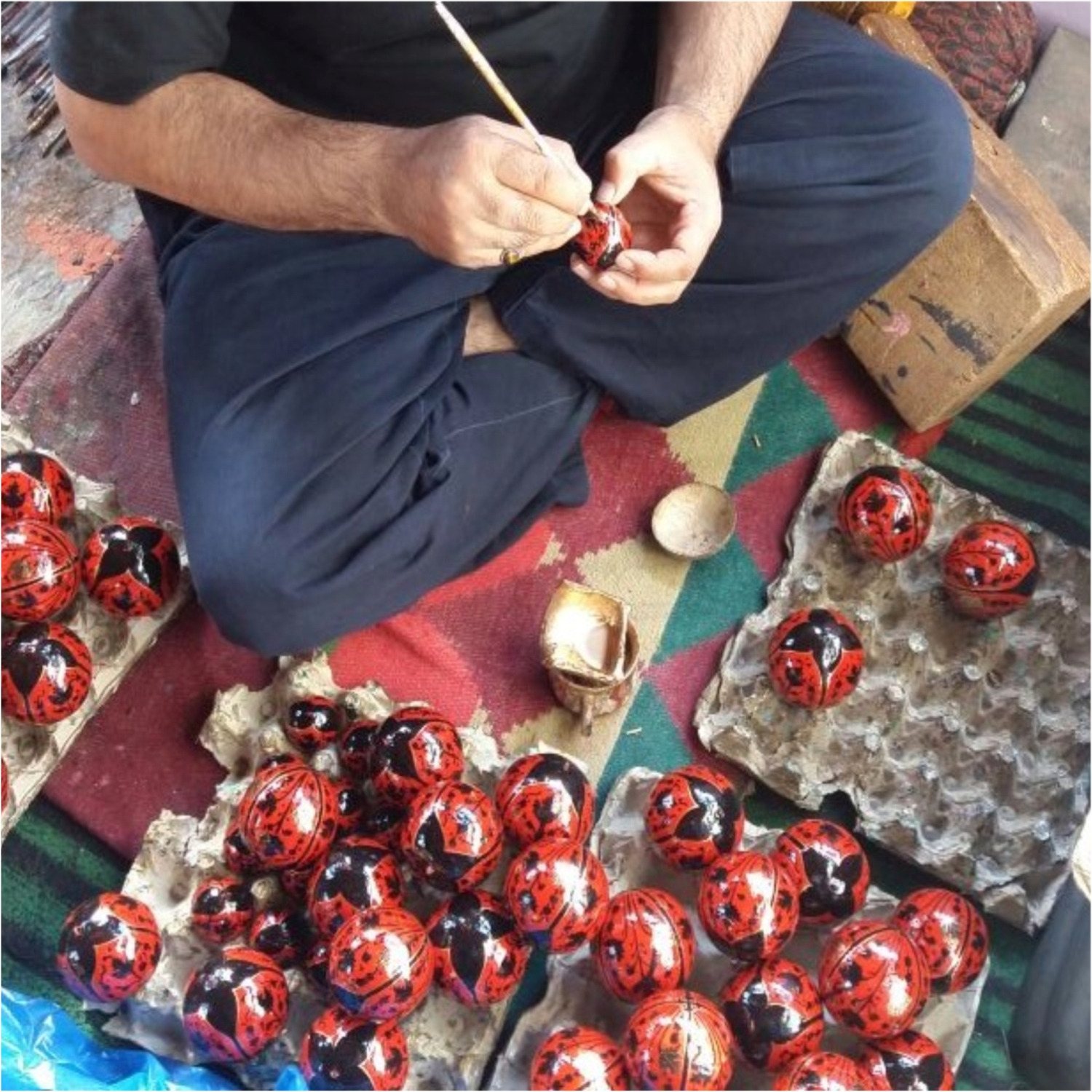 Artigiano in Kashmir durante la lavorazione manuale delle palline di Natale in cartapesta di riso